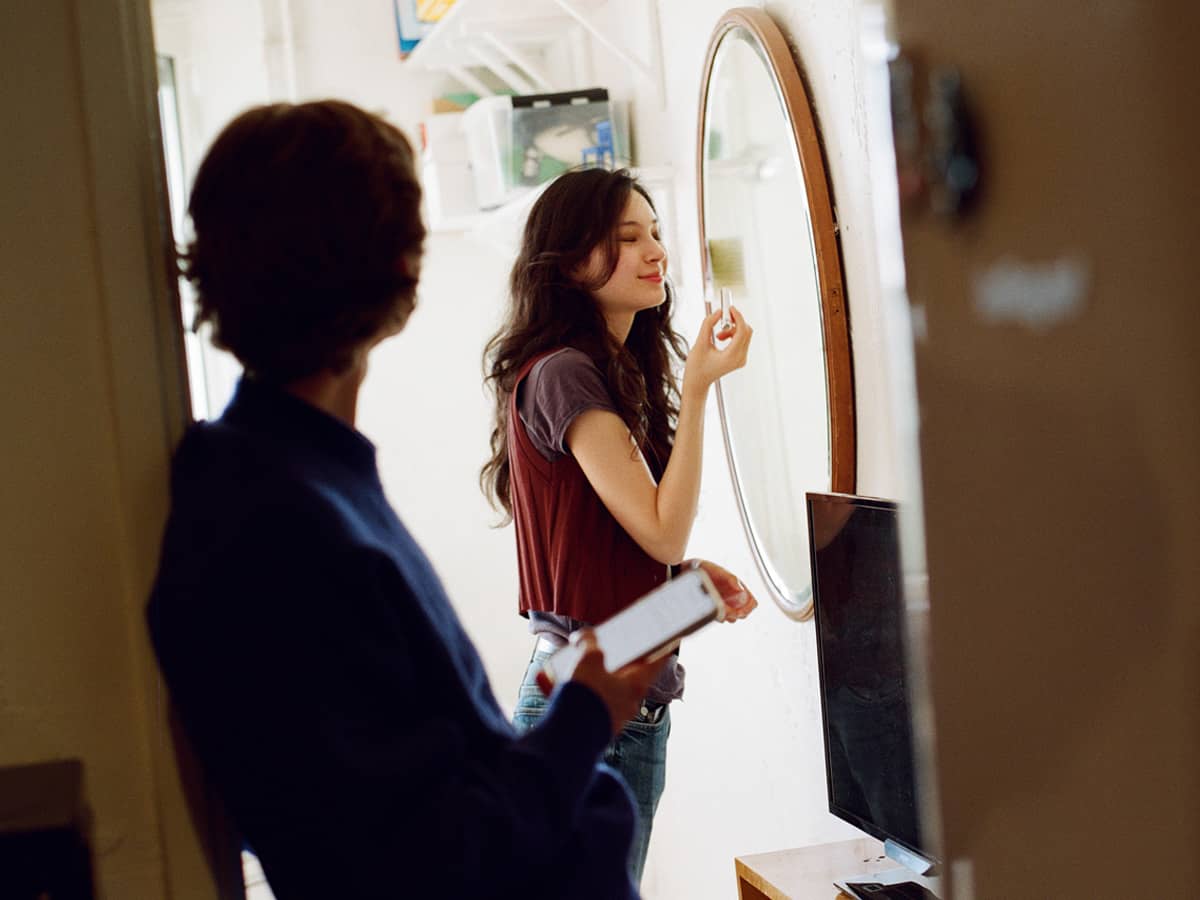 En tjej sminkar sig framför spegeln i sin lägenhet