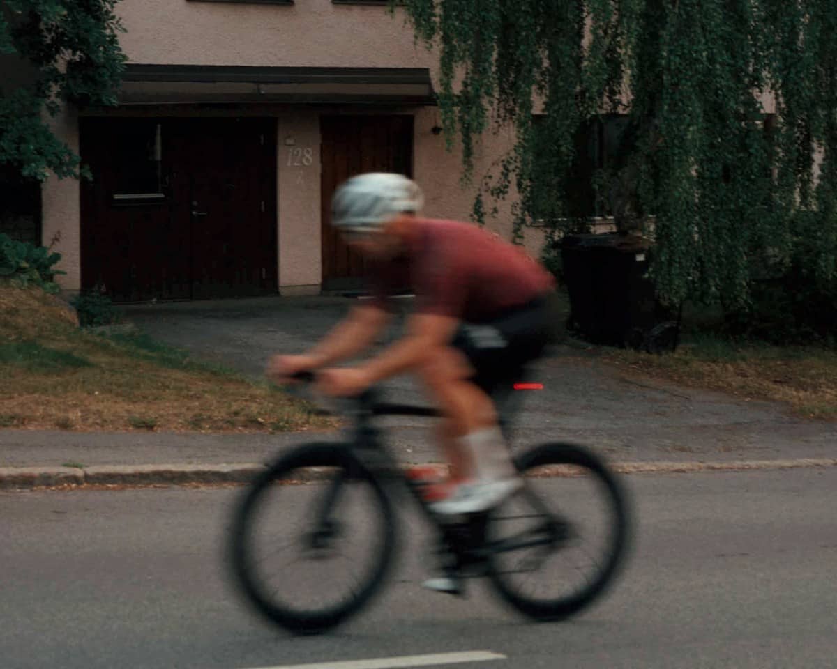 En person i vit hjälm cyklar upp för en gata