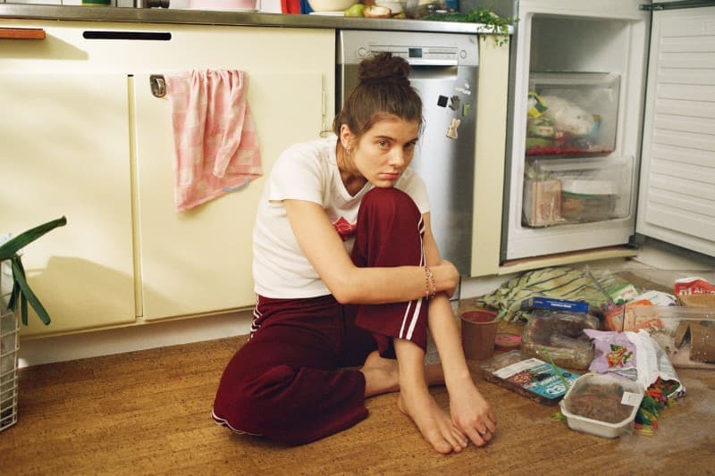 Kvinna sitter på golvet i köket med frys som har gått sönder