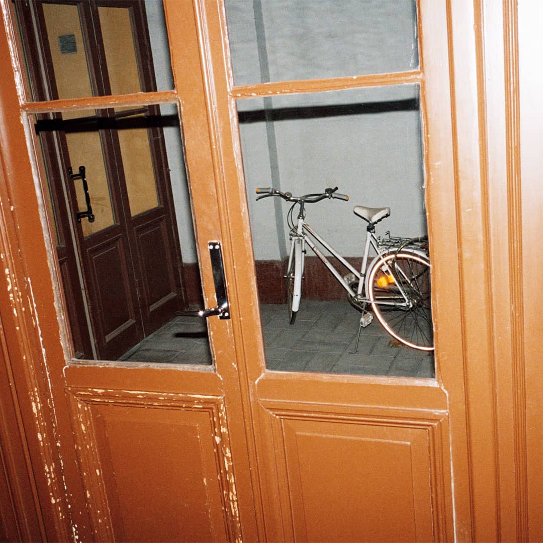 En vit cykel utanför en port i ett bostadshus