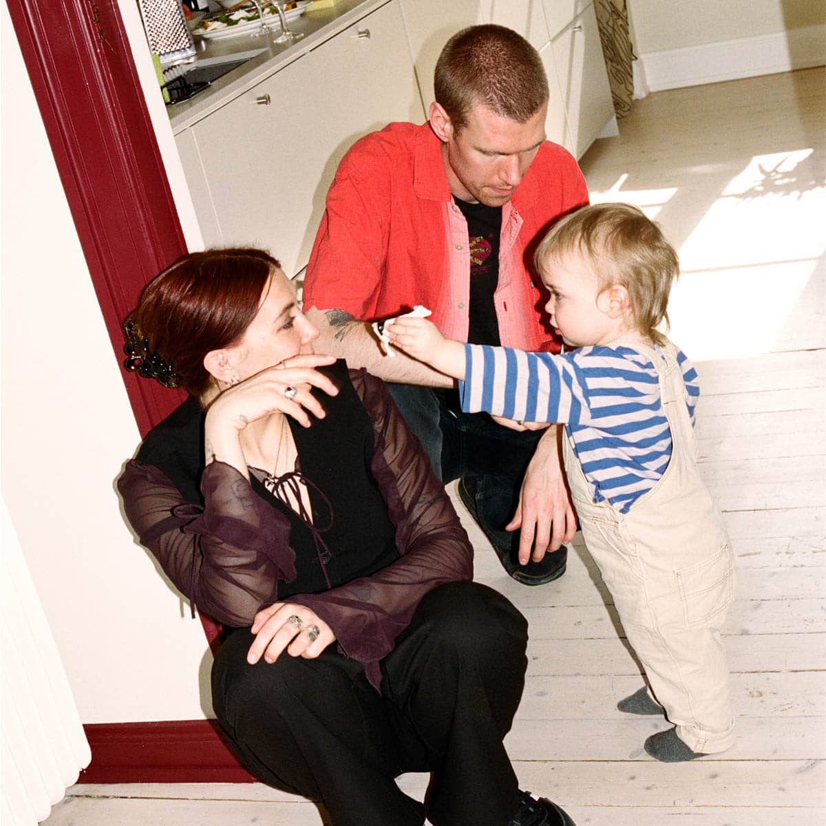 Mamma och pappa sitter på golvet med sitt barn i sin lägenhet