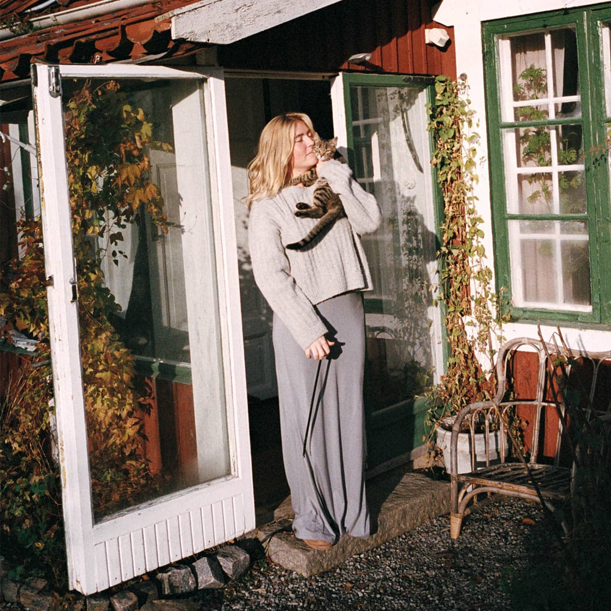 Katt i famnen på matte utanför en sommarstuga