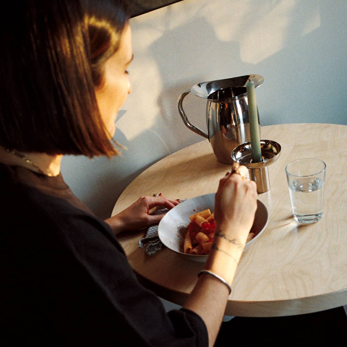 Tjej sitter vid ett matbord och äter pasta