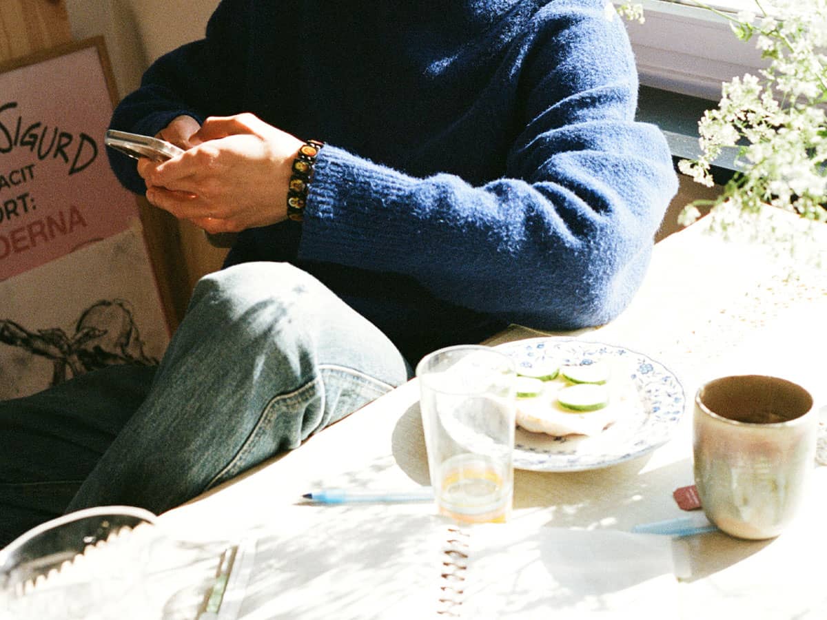 Person håller i telefon vid matbord