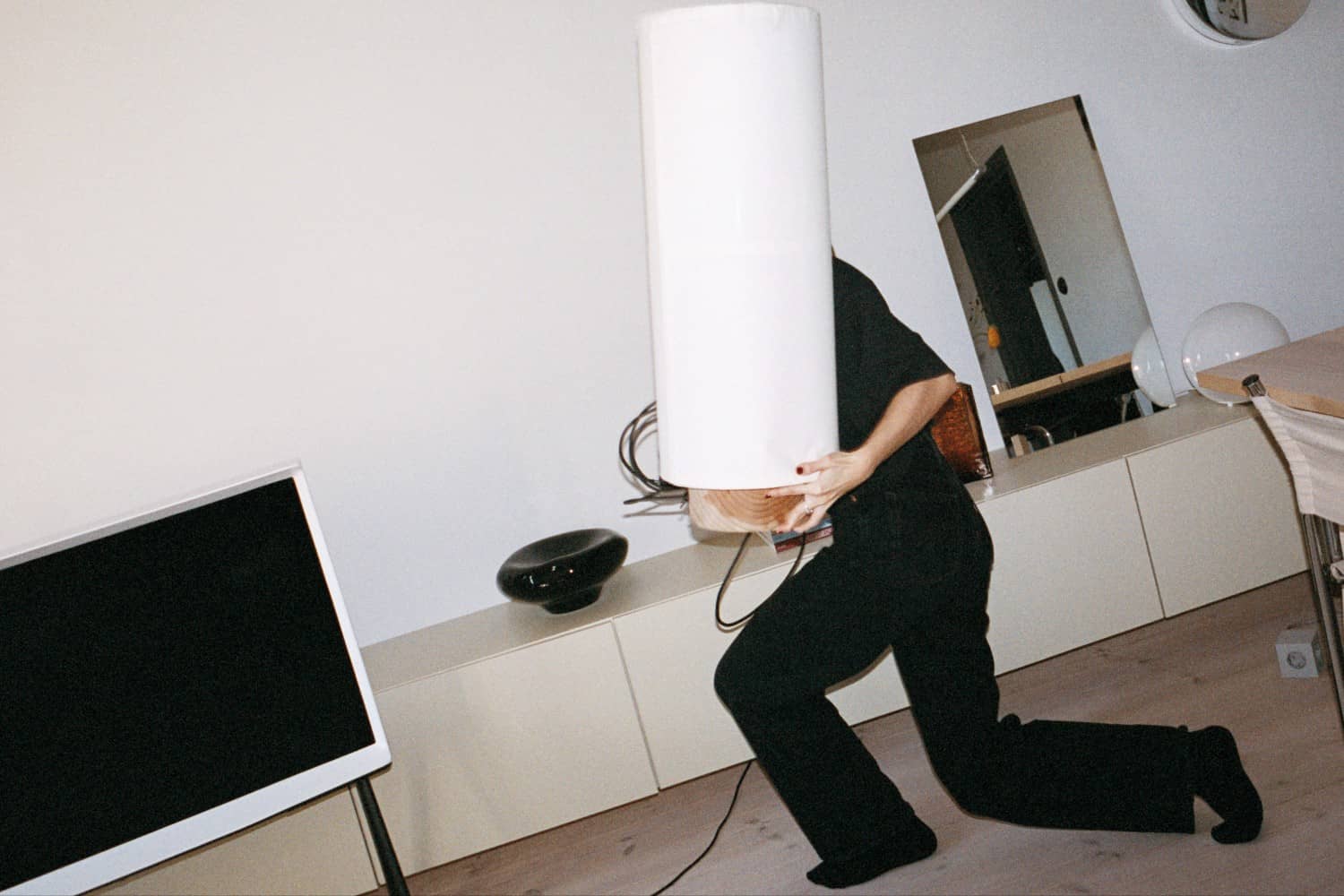 Person bär vit lampa bredvid TV i vardagsrum