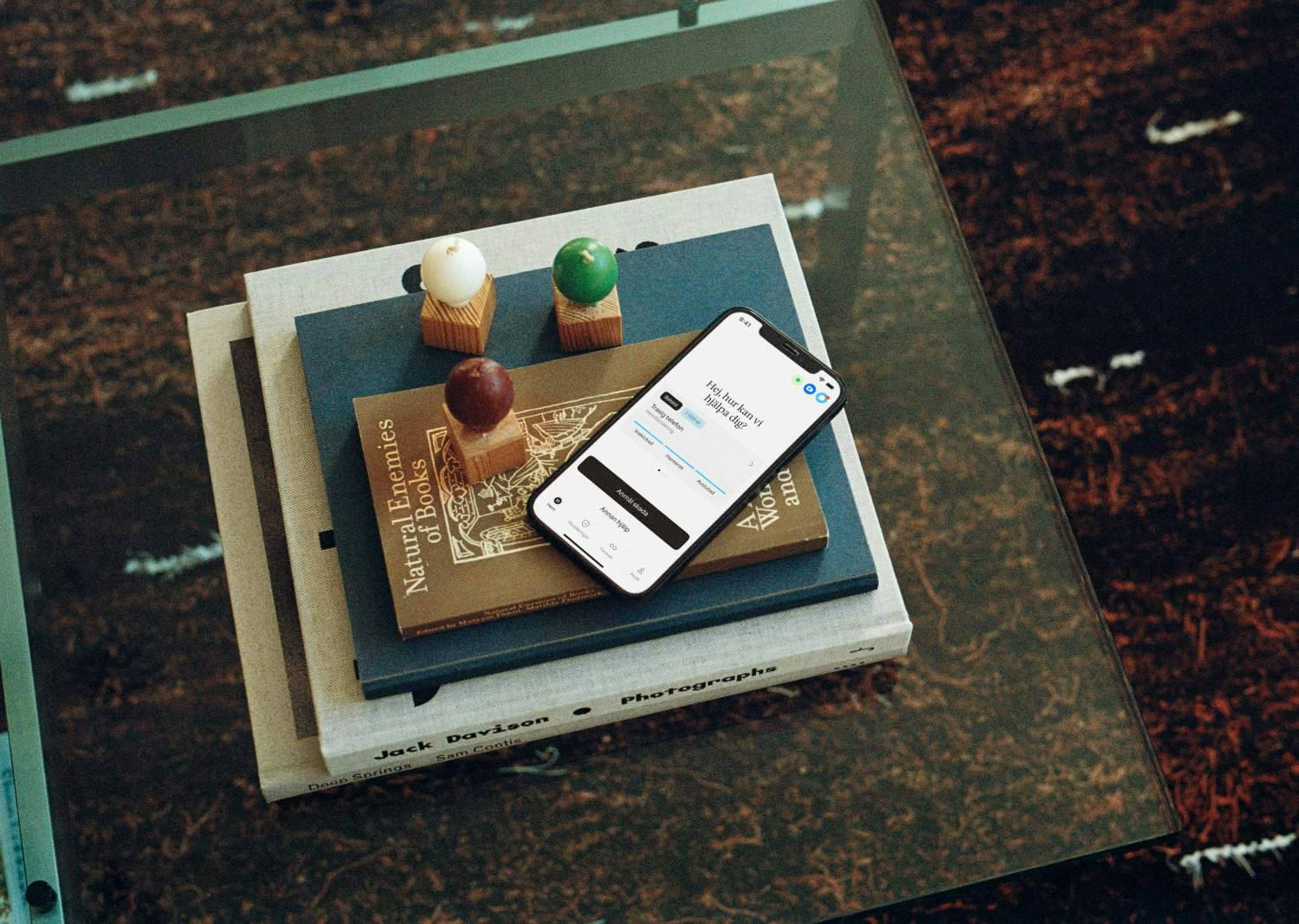 Mobiltelefon ligger på böcker på ett glasbord.