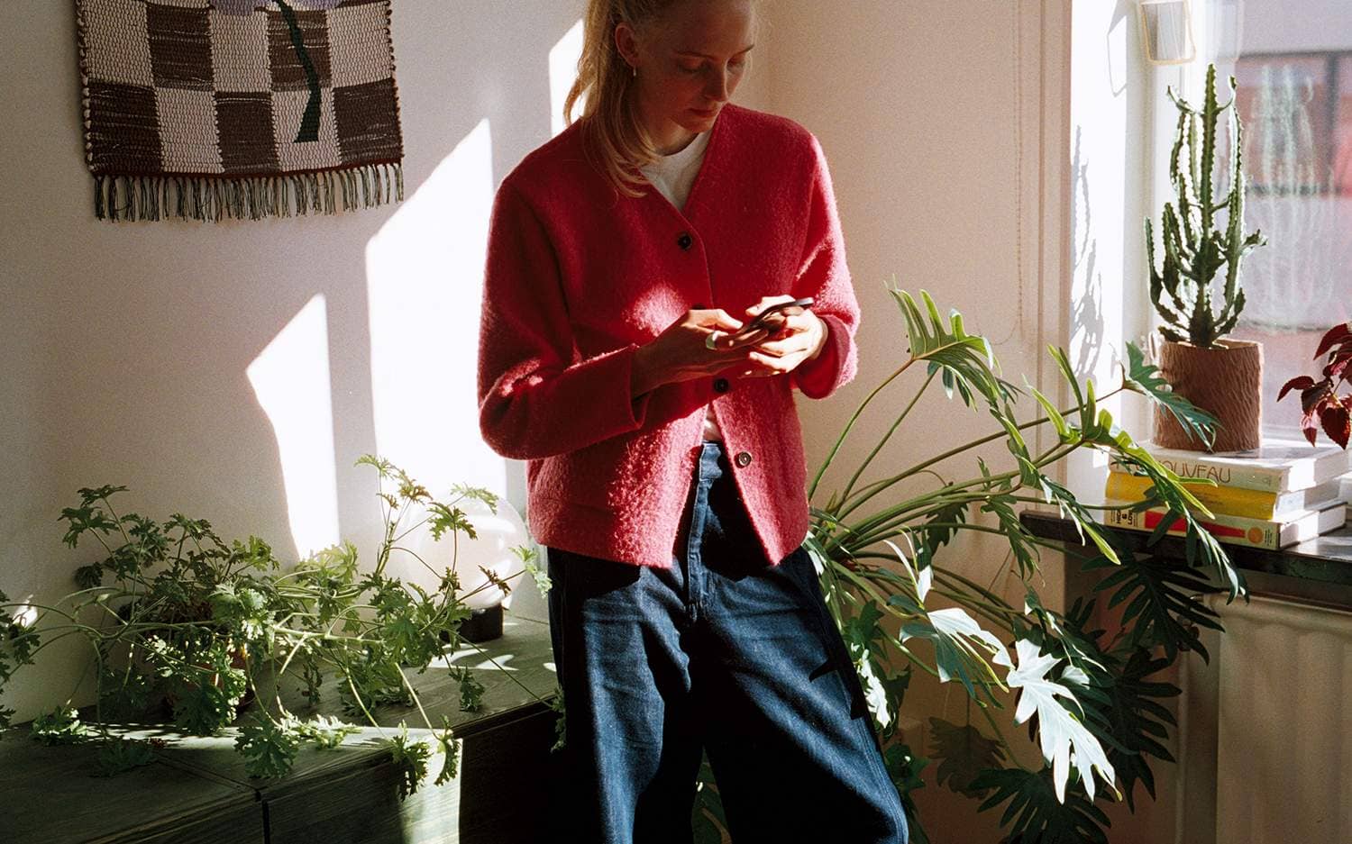 Person i sin lägenhet knappar på mobilen.