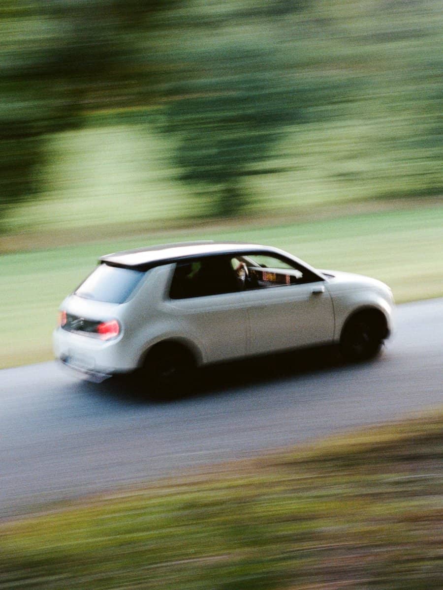 Vit bil i oskärpa kör på landsväg