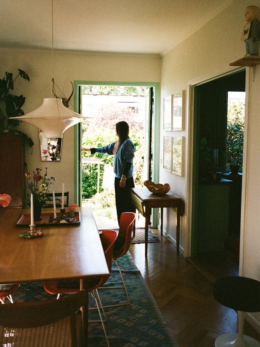 Kvinna står i dörröppning i sin villa, bild inifrån huset