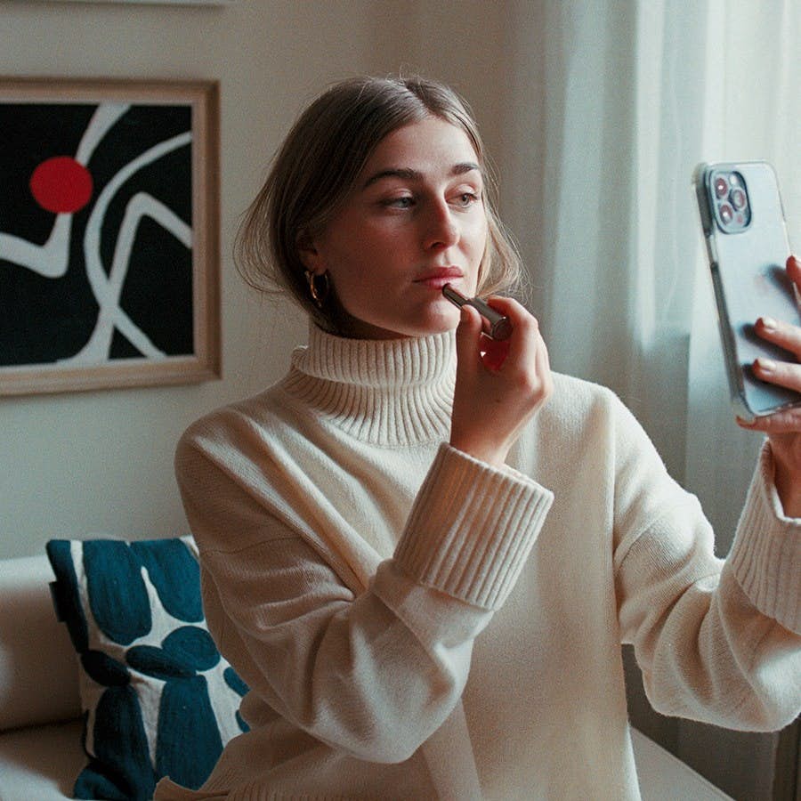 Viola Bergström sminkar sig med mobilen som spegel.